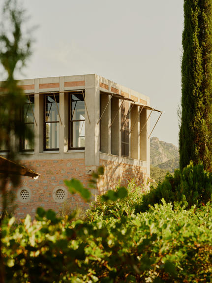 Library Tower at Amanruya, a stone structure framed by cypress trees and green hedges, in Turkey.