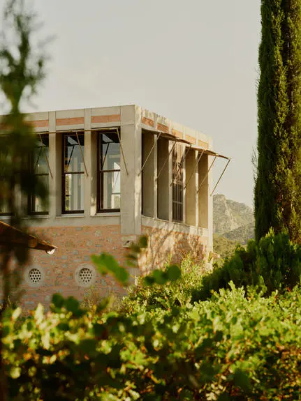 Library Tower at Amanruya, a stone structure framed by cypress trees and green hedges, in Turkey.