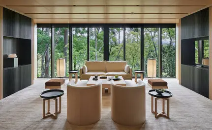 Suite at Aman Kyoto with floor-to-ceiling windows overlooking garden, wooden platform bed, and minimalist furnishings.