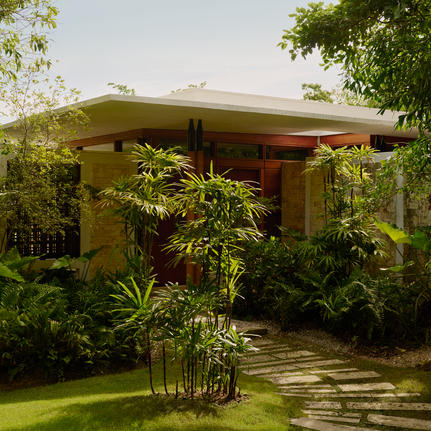 Exterior accommodation pavilion at Amanera resort, surrounded by lush tropical vegetation and a manicured lawn.