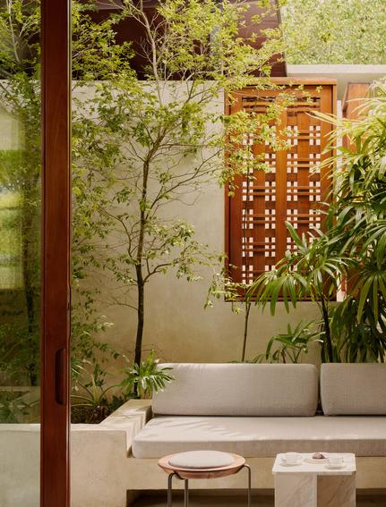 Outdoor seating area at Amanera resort with wooden furniture and climbing vines on textured walls.