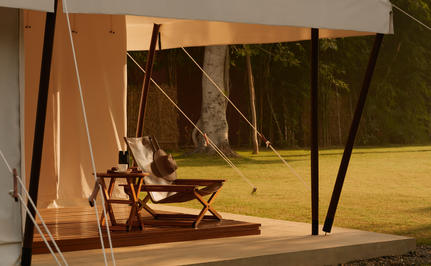 Candlelit lounge tent at Aman-i-Khas with open sides, wooden furnishings and warm evening light.