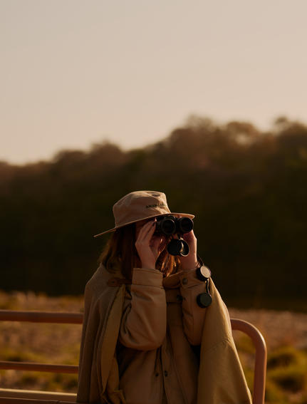 Safari guide at Aman-i-Khas observing wildlife through binoculars at dusk.
