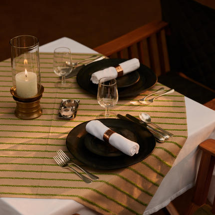 Private dining setup at Aman-i-Khas with candlelit table, place settings and wine in jungle setting.