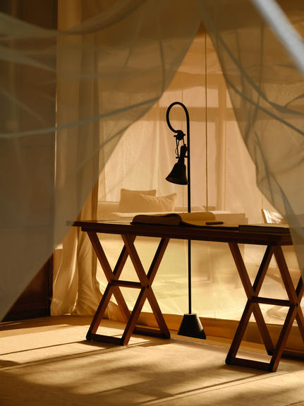 Candlelit workspace inside an Aman-i-Khas lounge tent, with a desk and chair beneath translucent fabric.