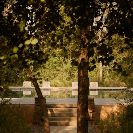 Wooden deck framed by tree branches overlooking a tranquil water feature at Aman-i-Khas.