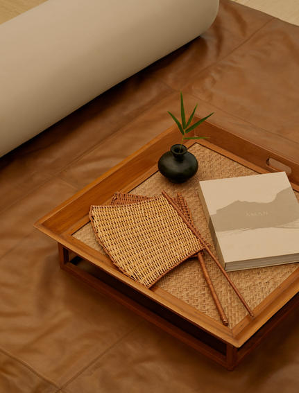 Wooden tray with woven details, small plant and open book inside an Aman-i-Khas tent.