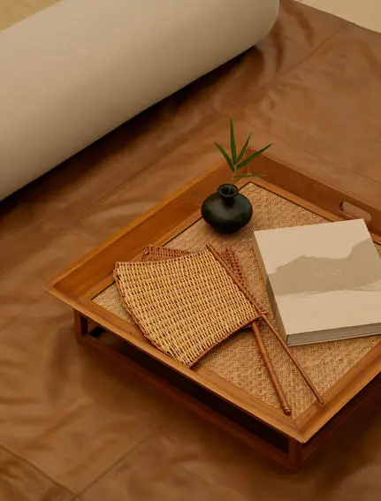 Wooden tray with woven details, small plant and open book inside an Aman-i-Khas tent.