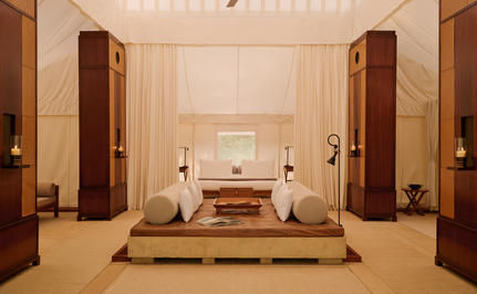 Spacious tent living area at Aman-i-Khas with neutral tones, wooden pillars, and central seating arrangement.