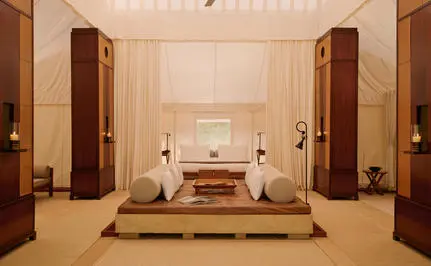 Spacious tent living area at Aman-i-Khas with neutral tones, wooden pillars, and central seating arrangement.