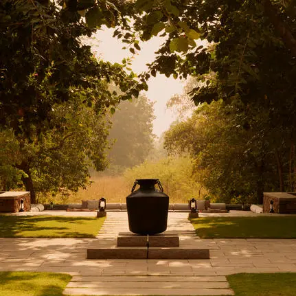 A central plunge pool at Aman-i-Khas framed by tree-lined pathways and dappled sunlight.
