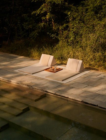 Two loungers on a stone deck beside a plunge pool at Aman-i-Khas, with illuminated greenery beyond.
