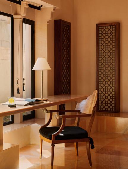 Pool Pavilion dressing room at Amanbagh with carved wooden screens and mid-century chair.