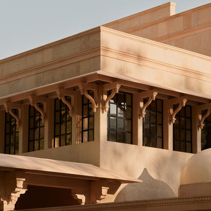 Amanbagh main building exterior detail showing carved wooden columns beneath a sandstone overhang.
