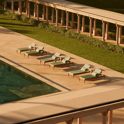 Sunbeds arranged along the poolside at Amanbagh, India, with covered pavilions beyond.