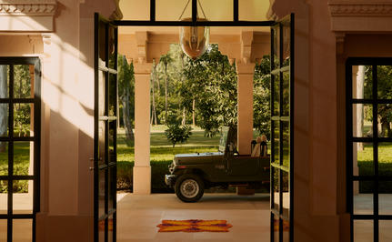 Vehicle parked at the entrance gates of Amanbagh, viewed through open wooden doors.