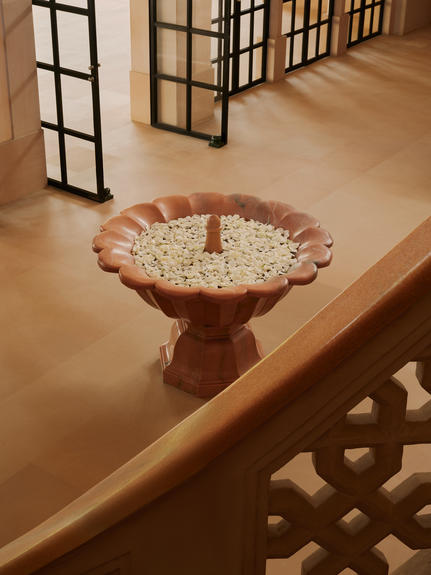 Terracotta bird bath filled with floating flowers at Amanbagh entrance.