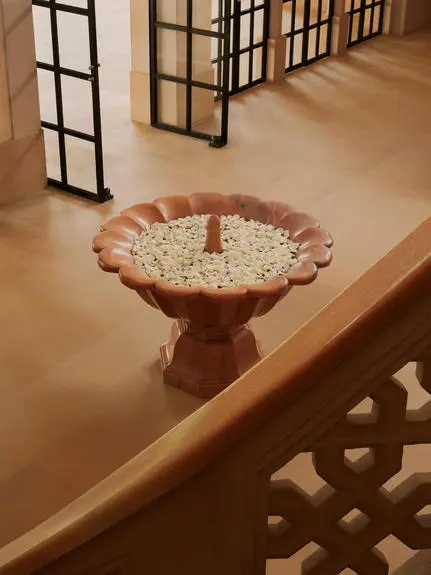 Terracotta bird bath filled with floating flowers at Amanbagh entrance.