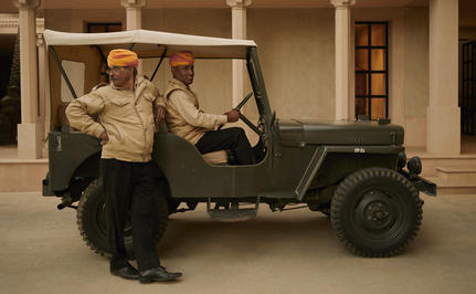 Group of staff members gathered around a vintage military jeep at Amanbagh.