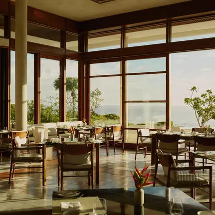 Amanera dining venue with wooden furniture and expansive windows overlooking Dominican landscape.