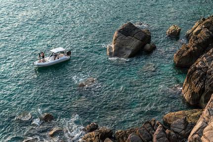 A small fishing boat on turquoise water near rocky cliffs at Amanoi.