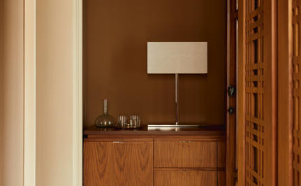 Hallway at Aman Venice with wooden console table, lamp, and warm brown walls.