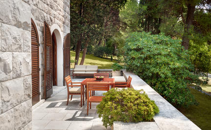 Stone terrace with wooden dining furniture overlooking the Adriatic Sea at Aman Sveti Stefan.