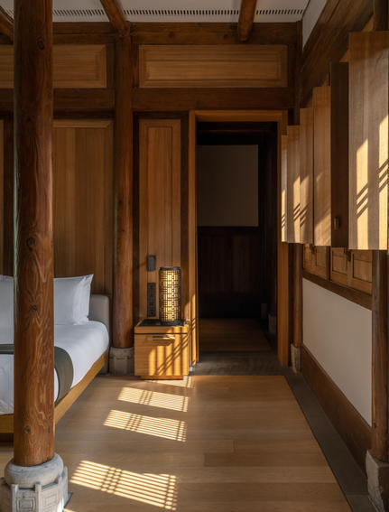 养云安缦度假村的木质走廊，阳光透过窗户洒落，墙上装有灯具。