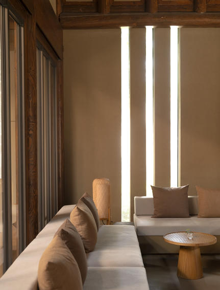 养云安缦度假村内一间卧室的一角,展示了极简主义设计,温暖的木质元素和柔和的自然光线。