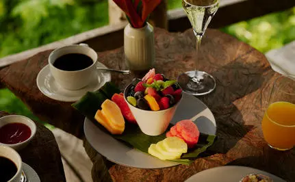Plato de frutas frescas y bebidas en una mesa al aire libre en Amanera resort.