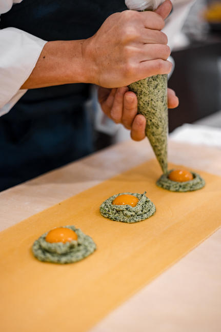 Hands presenting a dish at Aman Tokyo hotel, plating garnished food with precision.