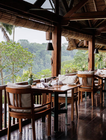 Dining pavilion at Amandari with wooden table and chairs overlooking verdant valley views.