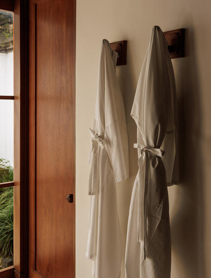 حمام في منتجع أمانداري بأوبود، بالي، إندونيسيا، يعرض مناشف كتانية معلقة على الجدار.