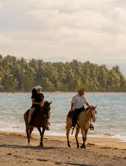 Dos jinetes a caballo en una playa tropical de Amanera resort, República Dominicana.