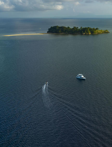 安缦湾澜度假村外的萨莱湾海域，一艘小船在平静的蓝色海水中航行。