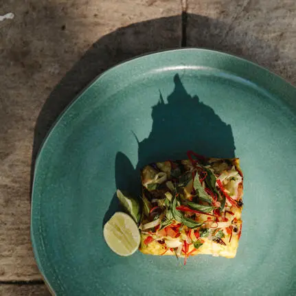 Grilled seafood fillet with lime and vegetables on a turquoise plate at Amanwana, Sumbawa, Indonesia.