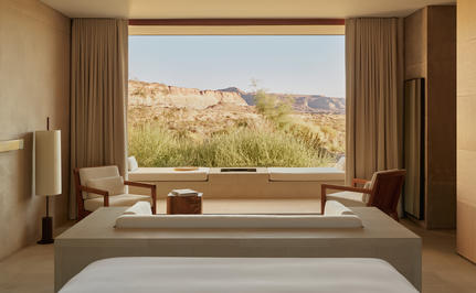 Desert suite bedroom at Amangiri with bed facing expansive window overlooking arid landscape.