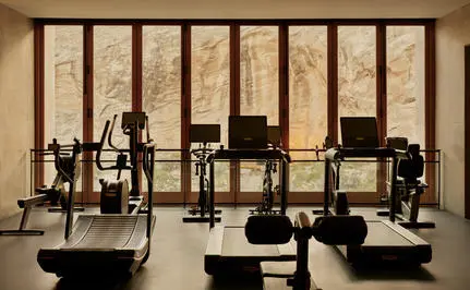 Amangiri gym with exercise equipment and floor-to-ceiling windows overlooking the desert landscape.