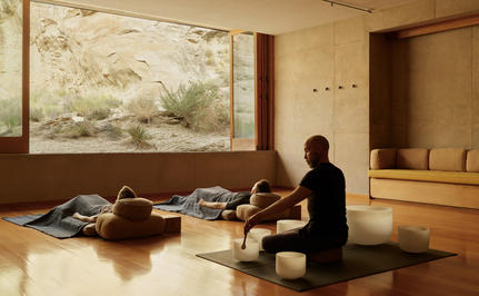 Person meditating in a serene studio at Amangiri, with natural light and minimal furnishings.