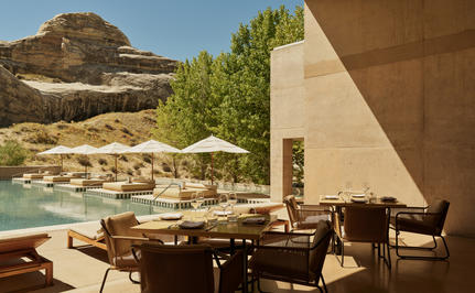 Amangiri's restaurant terrace with wooden dining furniture overlooking desert landscape and plunge pool.
