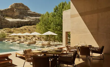 Amangiri's restaurant terrace with wooden dining furniture overlooking desert landscape and plunge pool.