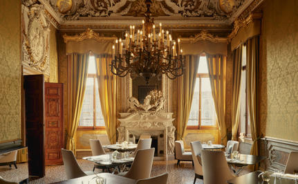 アマン ヴェニスのホテル内の、シャンデリアと窓から光が差し込む優雅なサロン。