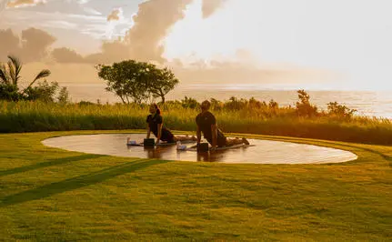Couple relaxing on expansive green lawn at Amanera resort at sunset.