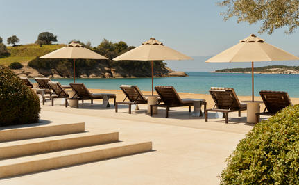 Amanzoe beach club with loungers and parasols overlooking the Aegean Sea.
