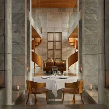 Formal private dining room at Amanzoe with marble columns, a central table set for two, and warm candlelit ambiance.
