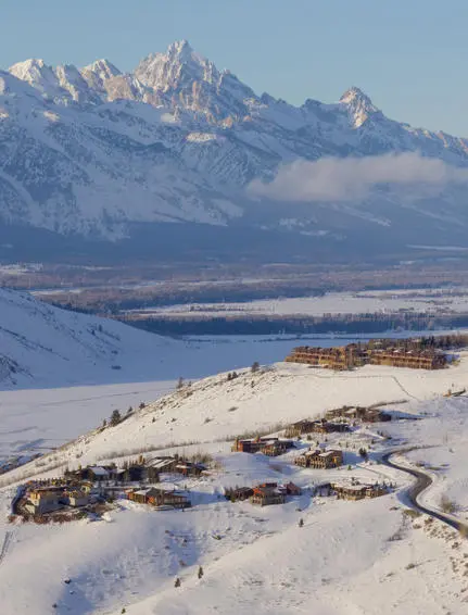 Snow-covered landscape surrounding Amangani in winter, with distant mountain peaks and valley below.