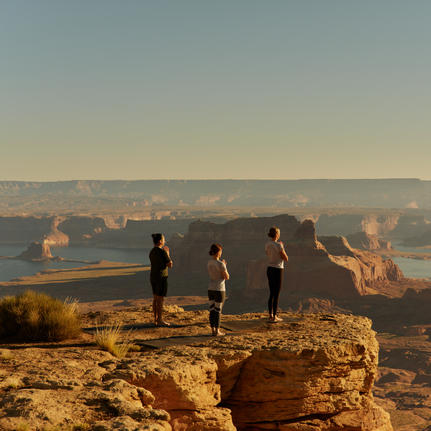 Guests practising yoga at sunrise on a rocky outcrop overlooking Tower Butte at Amangiri.