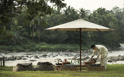 Staf Progo Picnic di Amanjiwo resort, Magelang, Jawa Tengah, bersantai di bawah payung putih di tepi sungai.