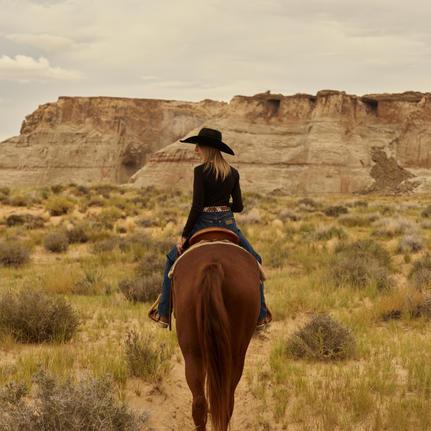 Rider on horseback across Utah desert landscape at Amangiri, summer.