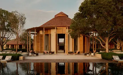 Bar at Amanyara resort reflected in still water at dusk, surrounded by trees.